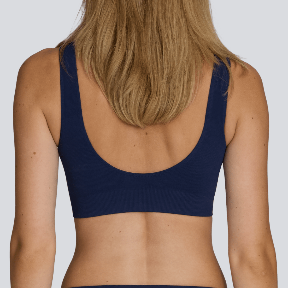 Navy blue sports bra worn by a person on a white background - Model:Emily